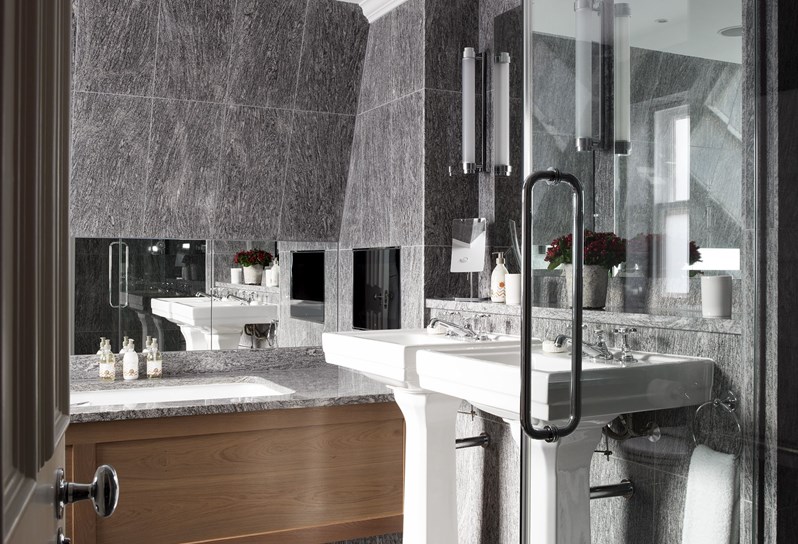 A granite bathroom with 2 basins, a bathtub and standalone shower in the corner.