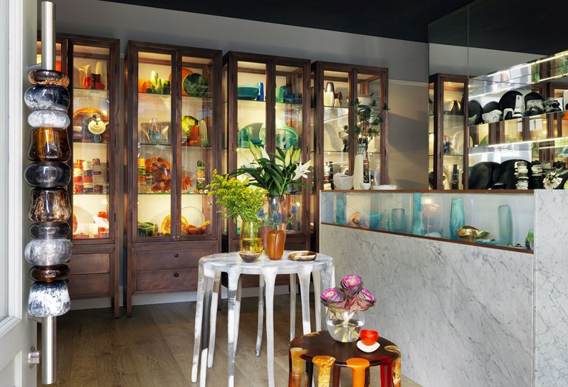 A small shop with large glass display cupboards in the back, a counter on the right and two display tables in front.