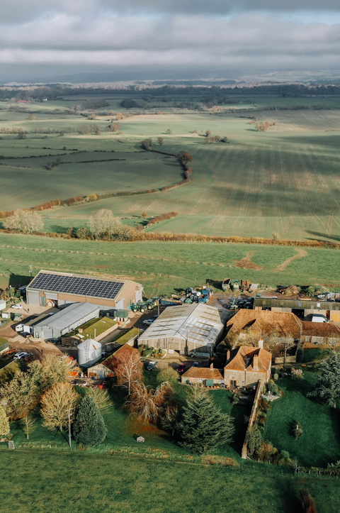 A far out shot of green landscape showing a farm and houses