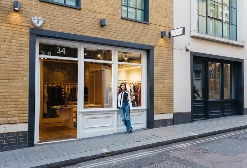 A women standing outside the Alta Store shop, clothes can be seen hanging inside