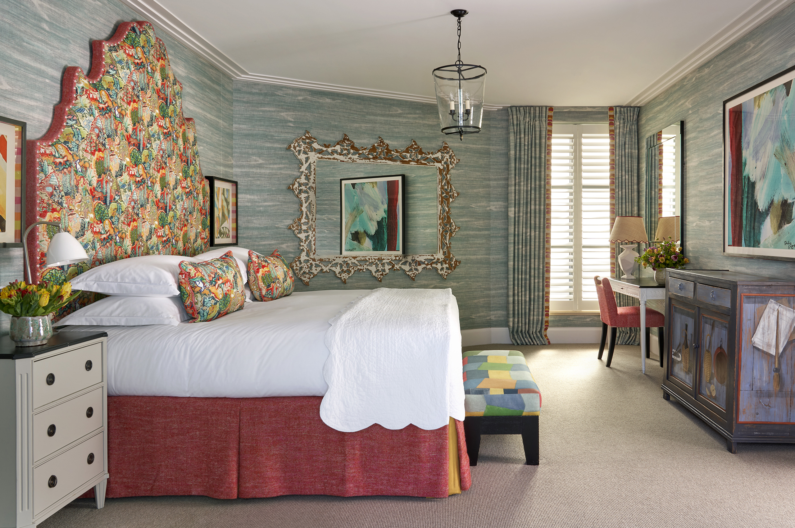 Colorful hotel bedroom with ornate headboard and white linens