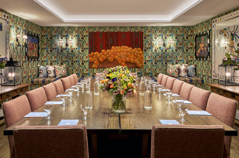 A squared meeting table set-up with notepad and glass of water in the Vanessa Bell private events room at Charlotte Street Hotel