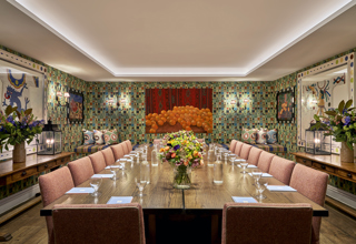A squared meeting table set-up with notepad and glass of water in the Vanessa Bell private events room at Charlotte Street Hotel