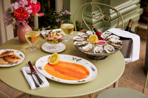 A table of main courses shot outside at Oscar. Dishes of smoked salmon, prawn cocktail and oysters to share
