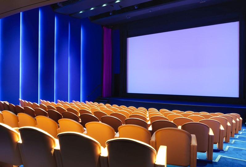 Angled view of electric blue walls and bright orange leather chairs in Ham Yard Hotel's state-of-the-art screening room.