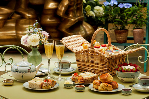 A wide shot of the items from the Wimbledon-themed Afternoon Tea at Ham Yard: this is being served on a table in the courtyard with two glasses of Champagne