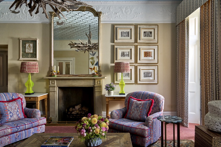 A landscape image of the drawing room at Number Sixteen, focusing on the armchairs and fireplace. 