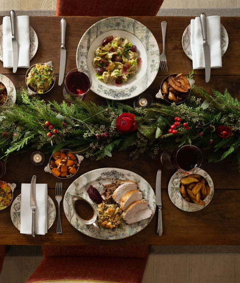 This a landscape image of a festive dining scene at the Warren Street Bar, Warren Street Hotel, featuring different dishes from the festive menu including a seasonal pasta dish and a traditional roast dinner served on Tall Tress Fine Bone China.