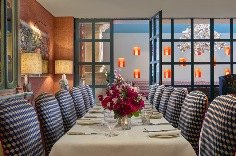 A wide angle shot of the drawing room at Warren Street Hotel set up for private dining: the table is set for twelve, and the windows look through to the Orangery
