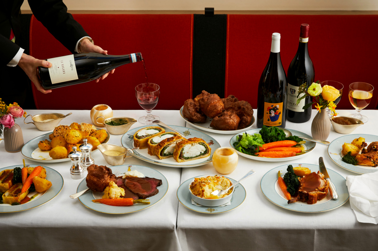 The Long Lunch at Ham Yard. A large table with three magnums of wine, sharing plates of meat and sides of potatoes, vegetables and cauliflower cheese