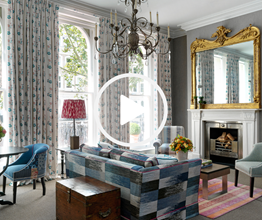 Image of living room with a blue sofa and a large gold mirror with a play button overlaid