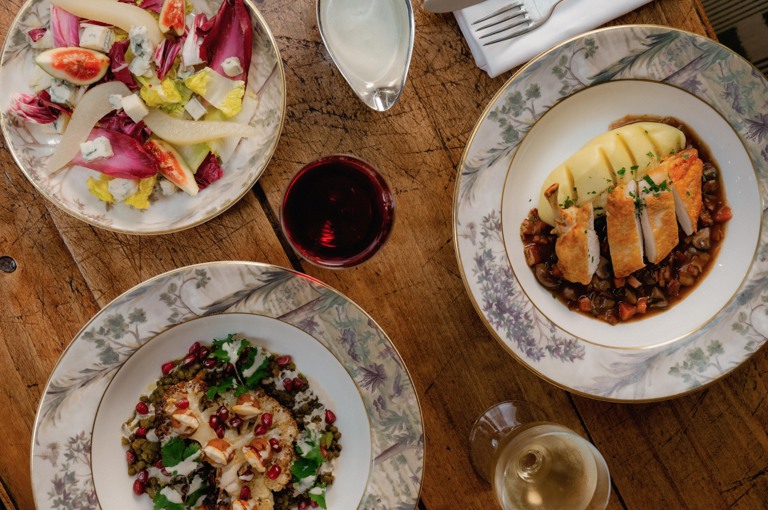 This image shows multiple dishes from The potting Shed, Dorset Squares, A La Carte Menu on Tall Trees Crockery, there is a chicken dish, a cauliflower dish and a salad. 