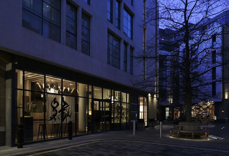 An evening shot of the exterior of a restaurant in soft lighting, with a Japanese sign in one of the windows.