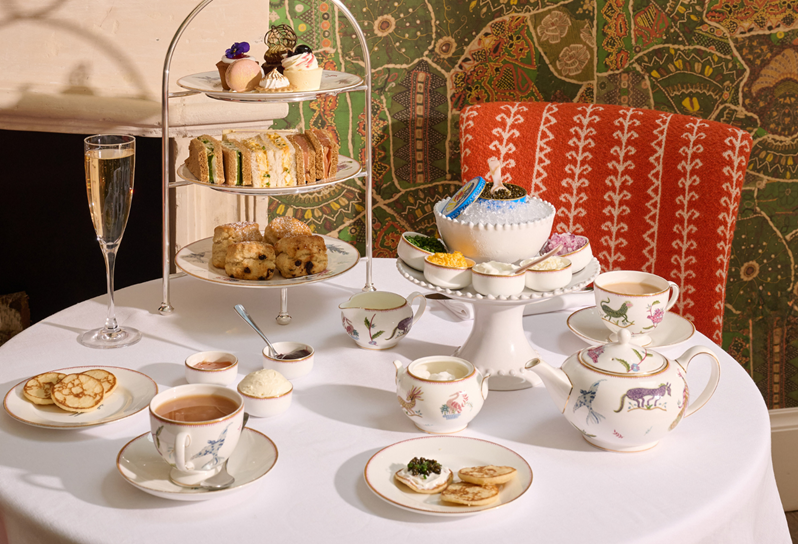 A table set for afternoon tea with cake stand, a teapot and tea cups and a plate of caviar