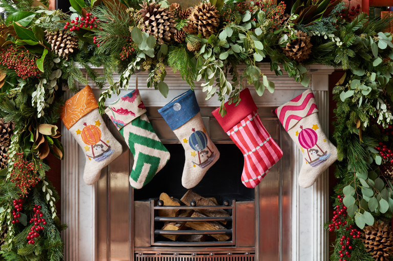 Firmdale festive stockings and Christmas decorations above and around a fireplace