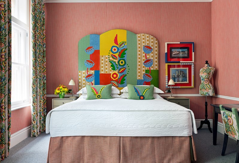 Beautiful patterned curtains and headboard over the bed with a small bedside table on the side
