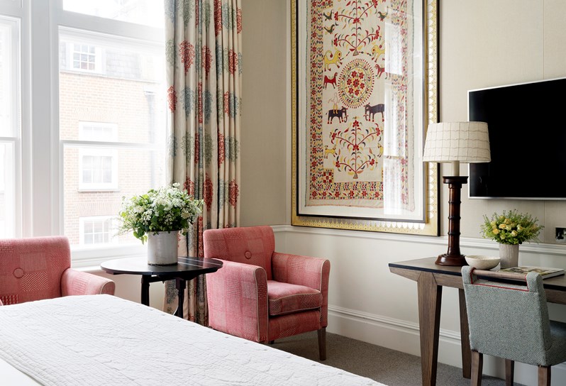Bedroom living room featuring an pink chair and coffee table. The room features floral curtains