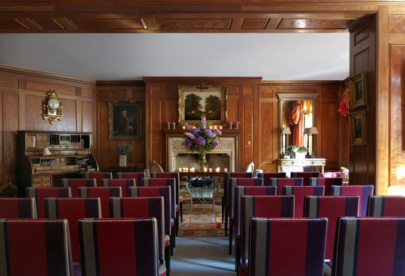 Drawing Room at Covent Garden Hotel with wooden wall panels and a fireplace and antique furniture set theatre style for a small wedding ceremony