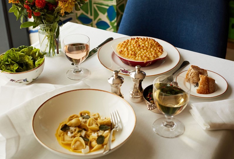 A table setting at Haymarket hotel restaurant with a bowl of pasta and a fish pie