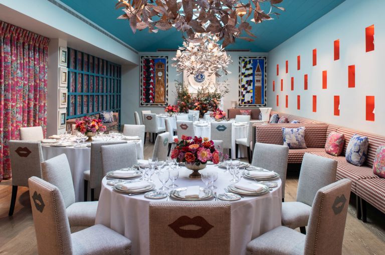 A Round dining tables set-up with dinnerware and glassware showcasing a chandelier and Orangery private events room at Warren Street Hotel