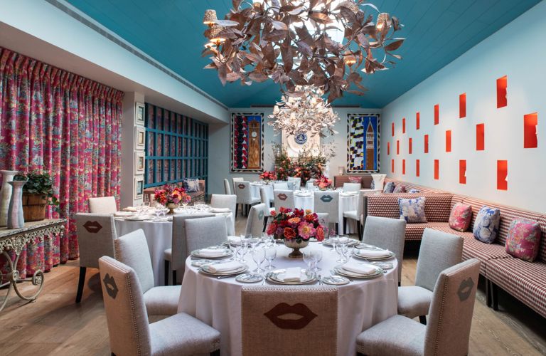 A Round dining tables set-up with dinnerware and glassware showcasing a chandelier and Orangery private events room at Warren Street Hotel