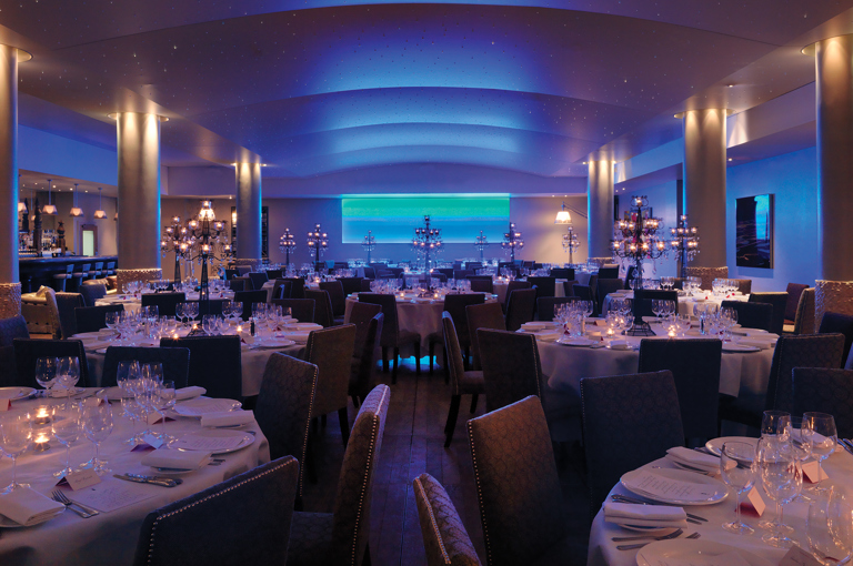 Wide shot of round dining tables in the Swimming pool private events room at Haymarket Hotel