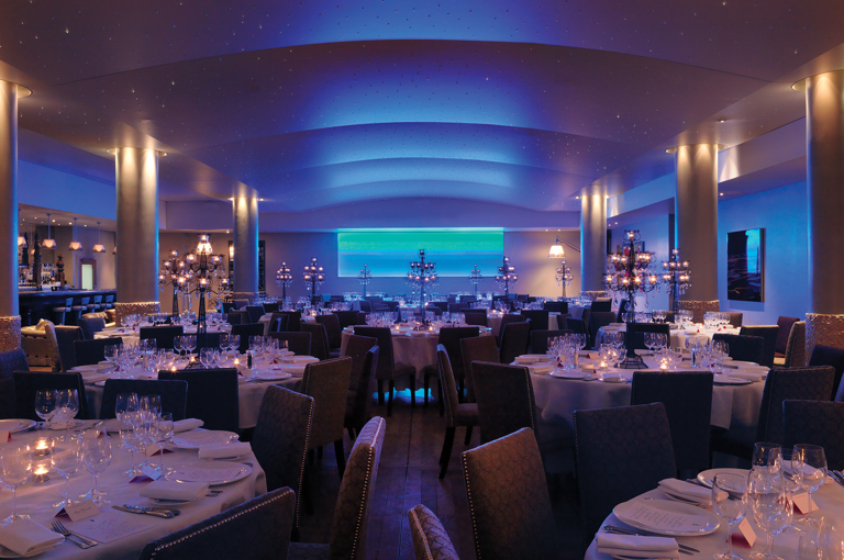 Wide shot of round dining tables in the Swimming pool private events room at Haymarket Hotel