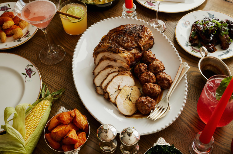 This image is shot from and angle in Oscar, at Charlotte Street Hotel, to promote the thanksgiving menu friendsgiving. The image shows multiple dishes from the menu including turkey, onion rings, ribs, roast vegetables, mac and cheese and lots of the themed cocktails. 