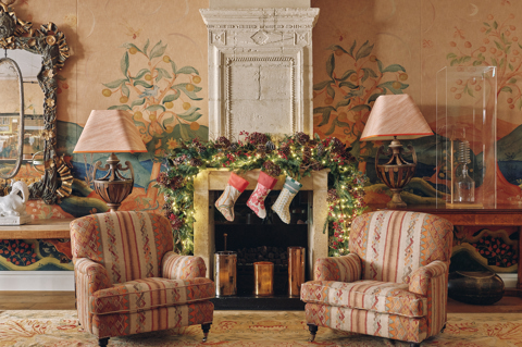 A landscape image of of Christmas decorations over the fireplace in the drawing room at The Soho Hotel. There is a festive garland draped over the fireplace behind two armchair.