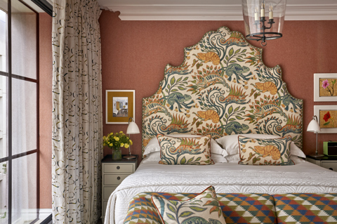 A close up shot of the bed featuring a colourful patterned headboard and sofa in a Deluxe Room at Ham Yard Hotel