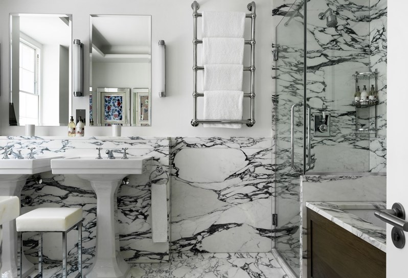 Luxurious bathroom designed in marble, with a large walk-in shower, separate bath tub, heated towel rack and double basins.