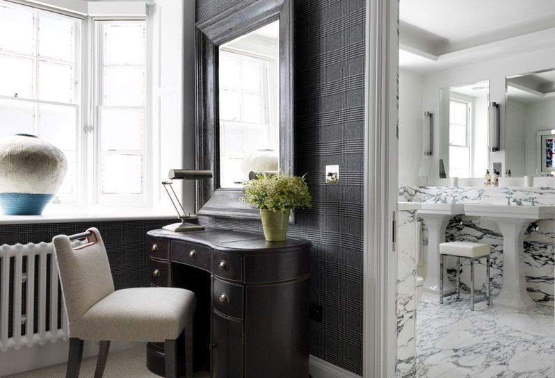 The dressing room entry way with a writing desk, chair and mirror leading into the marble bathroom with double basins.