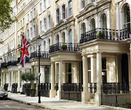 Beautiful townhouses in Knightsbridge, with a British flag and two large flower pots signalling the entrance to Knightsbridge Hotel.