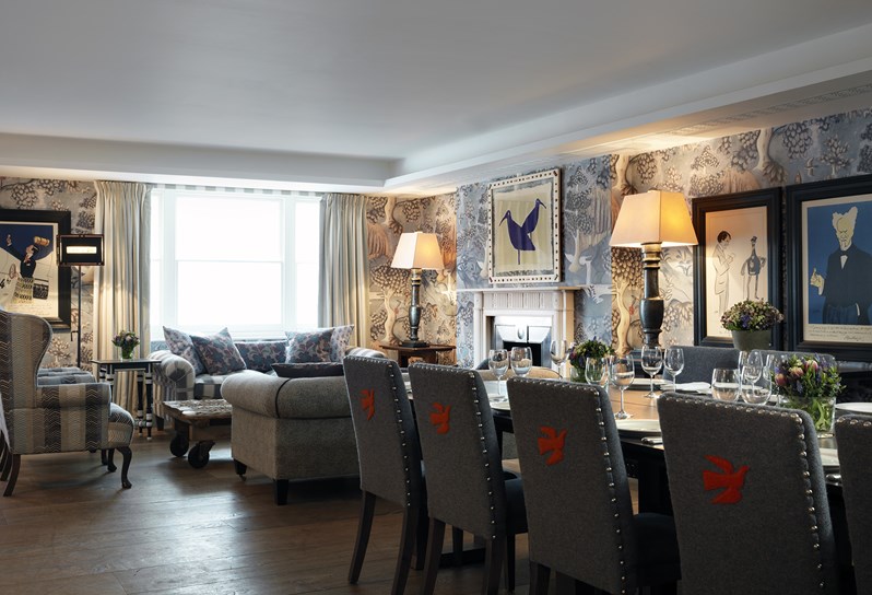 Haymarket Hotel Nash room. A dining table is set up in the foreground. In the background is a set of sofas and armchairs.