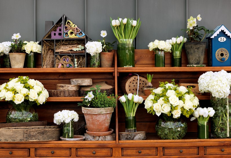 A wooden side table with vases of white flowers