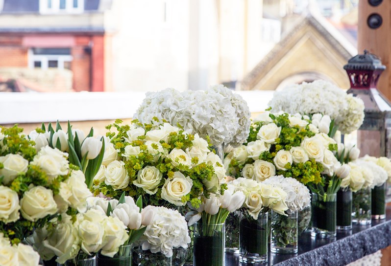 A row of white flowers on the Roof Terrace of Ham Yard Hotel with Soho rooftop views in the distance