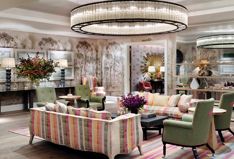 Prince Private event room has walls lined in a hand painted mural of trees. In the centre of the room is two colourful striped sofa and arm chairs surrounding a coffee table with fresh flowers and spectacular overhead ceiling lights.