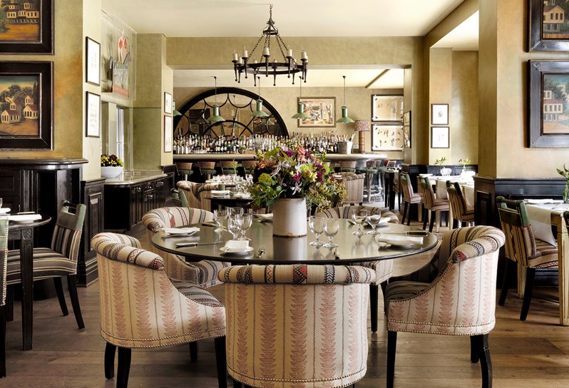 Shot of the restaurant with tables and colourful pink chairs showing the bar at the end.
