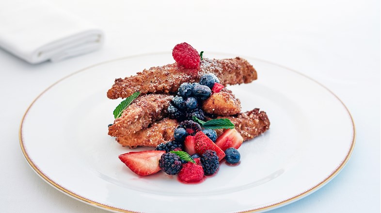 Close up image of Kashi Crusted French Toast with sliced strawberries, blueberries and raspberries.