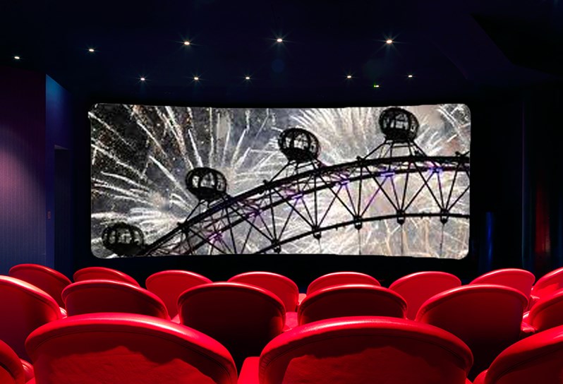 The Screening Room at Covent Garden Hotel. Rows of red cinema style seats point towards a cinema screen showing a fireworks display.