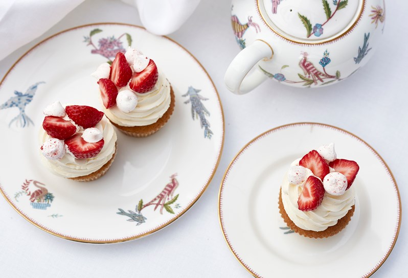 Cupcakes with white icing and strawberries on top.