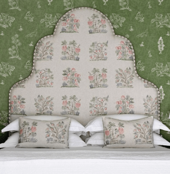 A bedroom setting showing a large fabric headboard and green wallpaper
