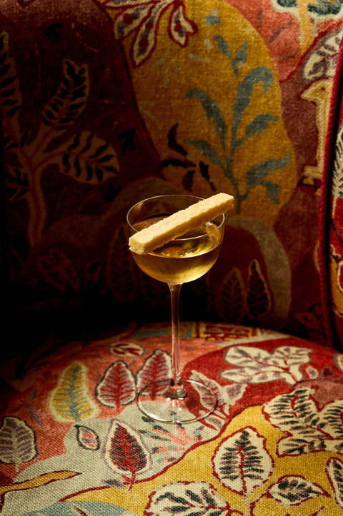 An image of a vodka based martini cocktail next to a bottle of Broken Clock vodka.