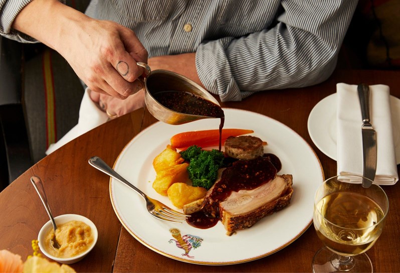 A Pork roast on a mythical creatures plate with a hand pouring gravy over the roast