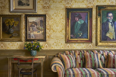 A close-up wide shot of the Drawing Room at Charlotte Street Hotel: A striped sofa sits next to an original table from the Omega Workshops
