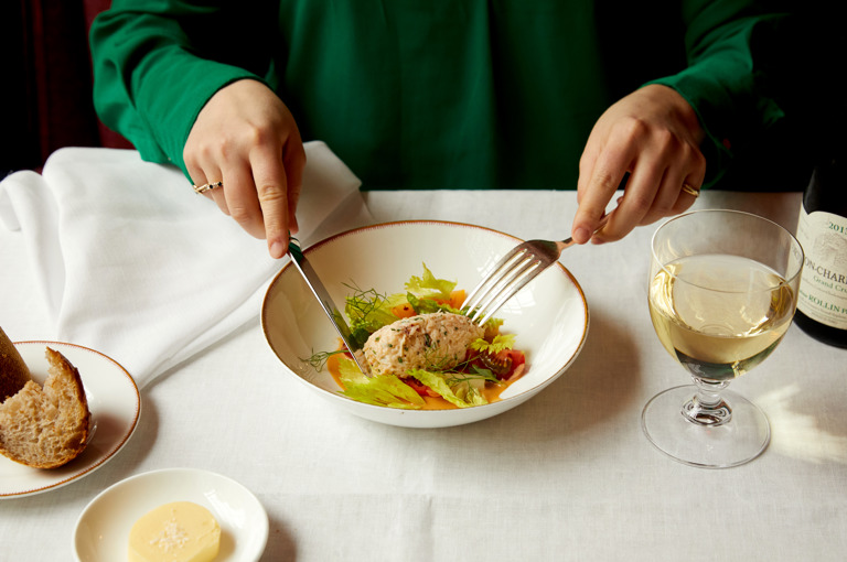 Two hands cut in to a starter of crab salad at Brumus