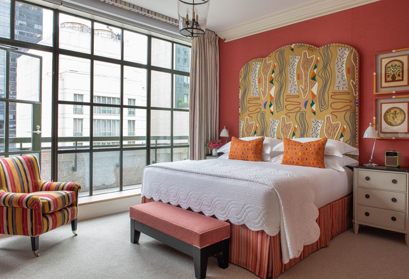 Blue bedroom in tones of yellow boasting a king size bed and Kit Kemp's yellow fabric