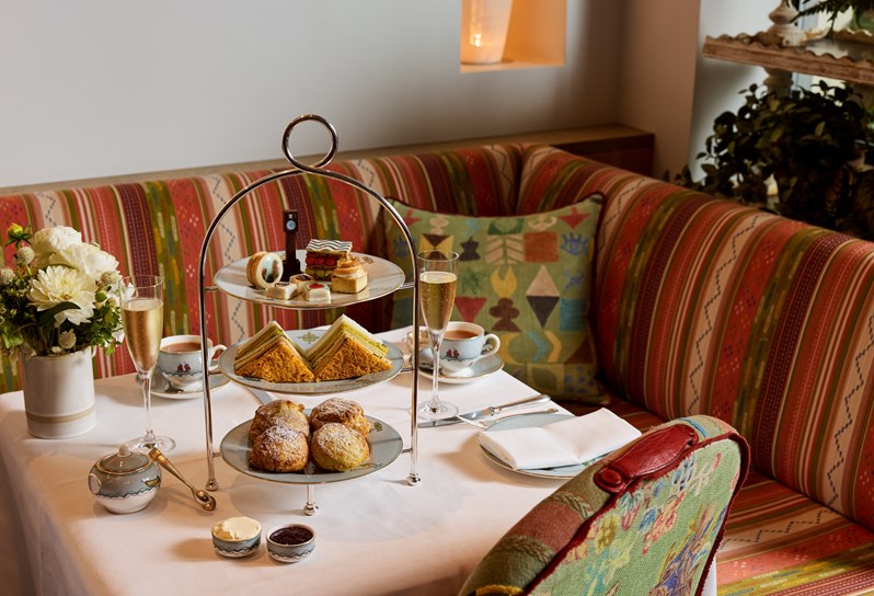 Willow's Art Walk Afternoon Tea at The Whitby Hotel. A cake stand displaying, sandwiches, scones and art-themed pastries and cakes, set up on a table with tea and Champagne.