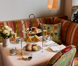 Willow's Art Walk Afternoon Tea at The Whitby Hotel. A cake stand displaying, sandwiches, scones and art-themed pastries and cakes, set up on a table with tea and Champagne.
