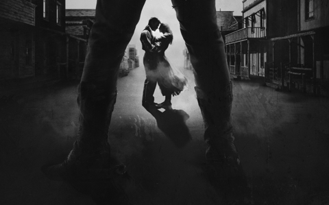 A man and a woman embrace in a black and white Western scene